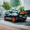 a black sports car with orange rims parked on a street