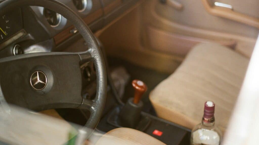 a bottle of alcohol sitting in the driver's seat of a car