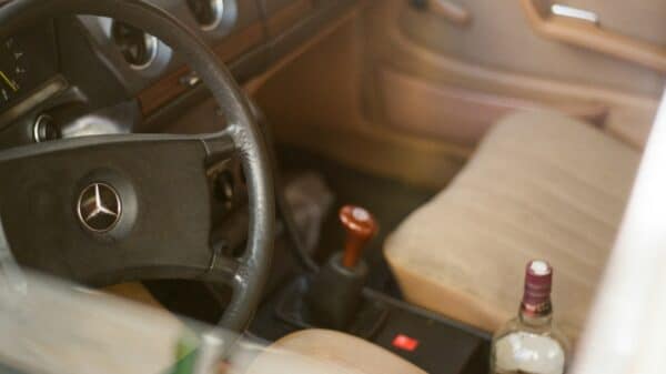 a bottle of alcohol sitting in the driver's seat of a car