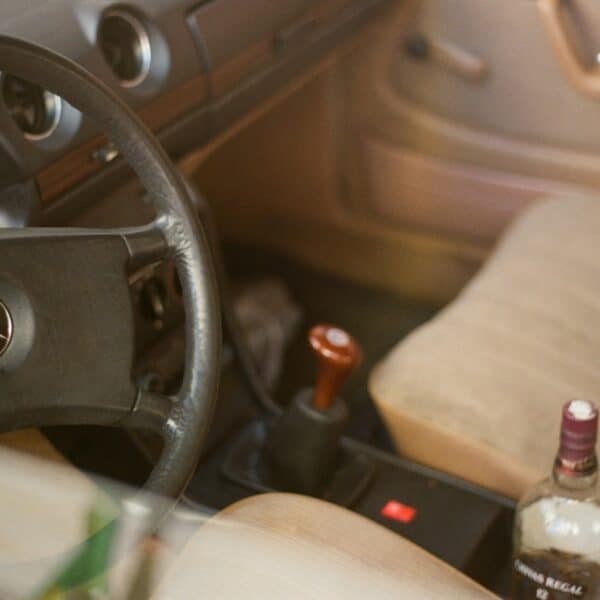 a bottle of alcohol sitting in the driver's seat of a car