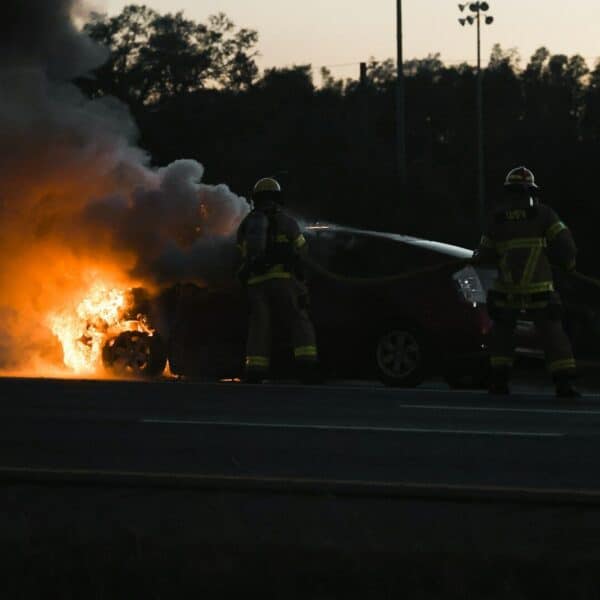 Two firemen are putting out a car fire