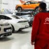 A man standing in a garage looking at cars