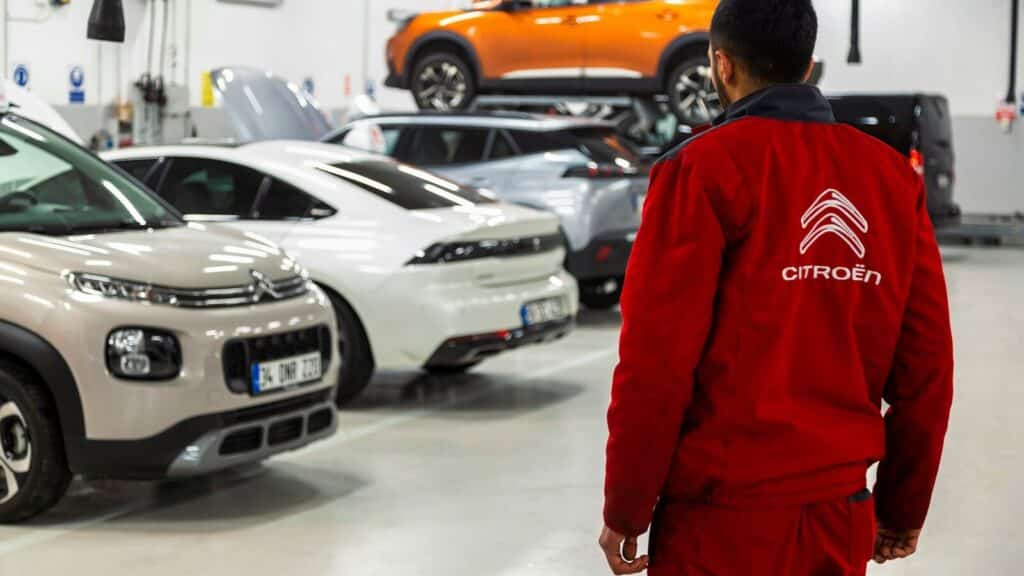 A man standing in a garage looking at cars