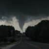a large tornado is seen in the sky over a road