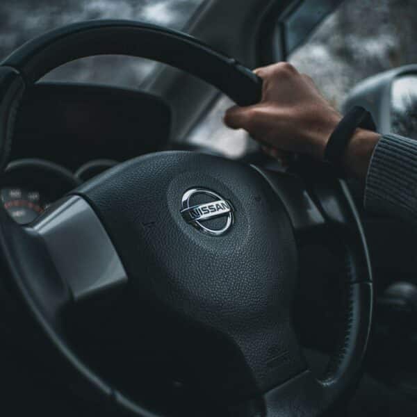 person holding black nissan steering wheel