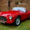 a red sports car parked in front of a brick wall