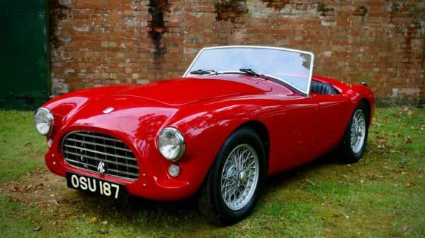 a red sports car parked in front of a brick wall