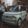 A mint green fiat 500 parked on a street.