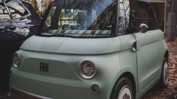 A mint green fiat 500 parked on a street.