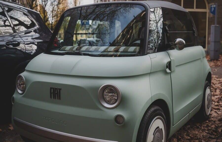 A mint green fiat 500 parked on a street.