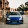 Blue sports car parked on a street with old buildings