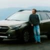 Man leaning on a car with mountains behind him