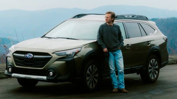 Man leaning on a car with mountains behind him