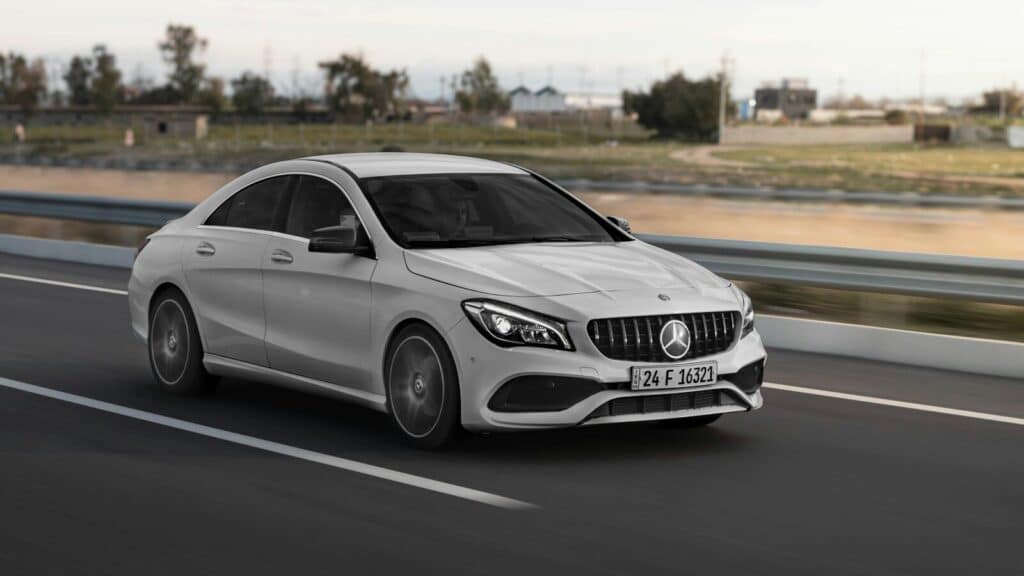 a white mercedes cla driving down a highway