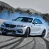 a white bmw car driving down a road