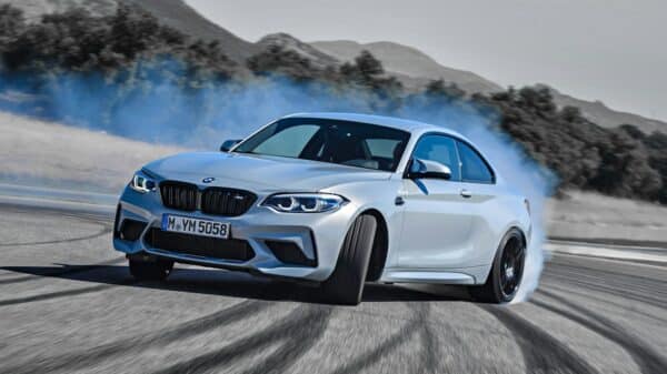 a white bmw car driving down a road